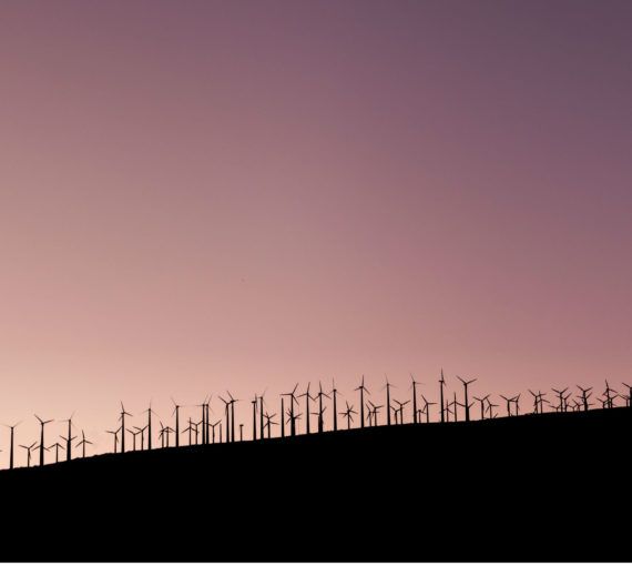 A picture of a wind farm on the horizon at dusk