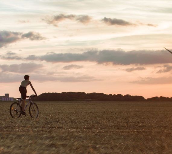 Cyclist in a field with wind turbine