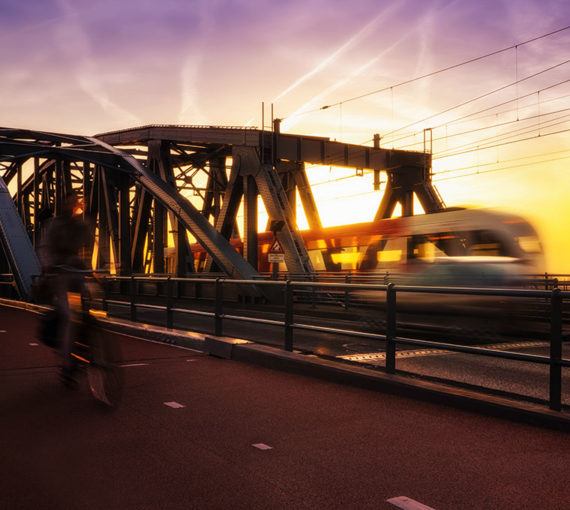 transit-active-transportation Cyclist and public transit commuter train share a bridge