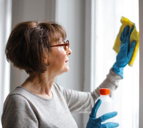 woman-cleaning-disinfecting-windows Woman cleaning a window