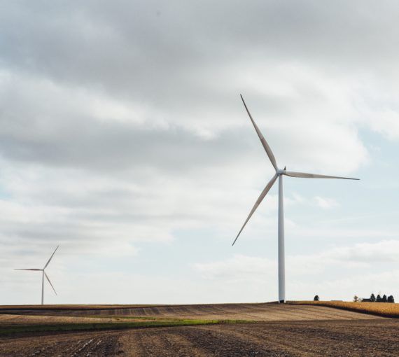 Two white windmills on brown field during the daytime