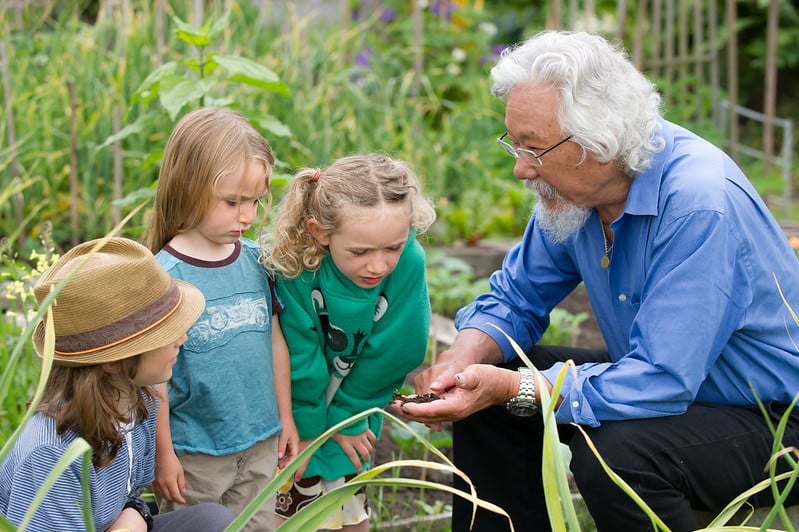 Children and man gather around garden